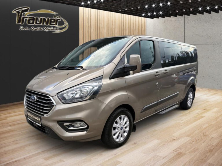 Silberner Ford Tourneo Custom Kleinbus in einem Autohaus, von vorn links gesehen