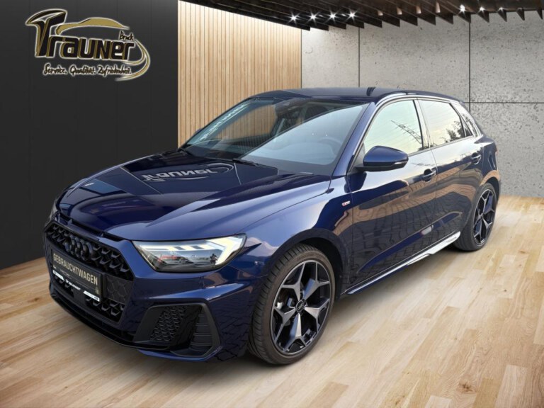 Dunkelblauer Audi A1 Sportback in Frontansicht schräg von links im hellen Autohaus-Ausstellungsraum